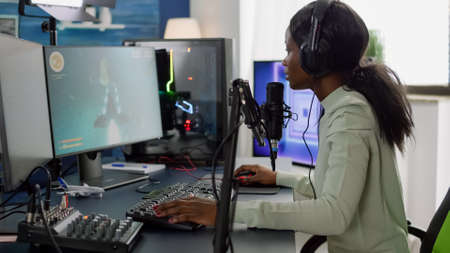 Competitive black gamer with headphones using stream chat on RGB powerful computer playing online...