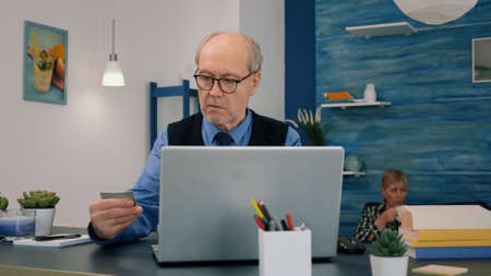 Retired man making shopping online doing payment using credit card on laptop working from home....
