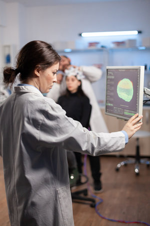 Neurology scientist examining brain nervous system scan on on monitor, machine with sensors attached...