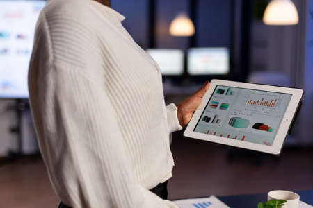 Closeup of african businesswoman holding tablet computer in hands while checking financial graph...