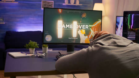 Over shoulder shot of man after losing at video games on computer using professional RGB equipment....