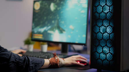 Close up of gamer using professional RGB mouse and keypad playing space shooter tournament in gaming home studio. Pro player streaming online video game during virtual championship on powerful computerの写真素材