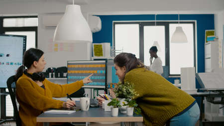 Graphic designers analysing client assets from displays checking color greading and taking notes....