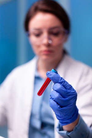 Close up of sample of with blood hold by scientist doctor in hospital. Researcher in chemical...