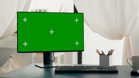 Powerful computer with chroma key green screen mock up stands on desk in living room. Pc with isolated display in home office with nobody in is ready for online business meetingの写真素材