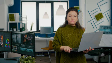 Employee looking at camera smiling standing in front of camera working in creative agency office...