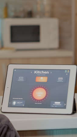 Young man using smart home application with voice command to turn on the light with digital tablet.