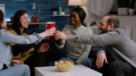 Afro american woman socialising with friends while having fun late at night in living room during...