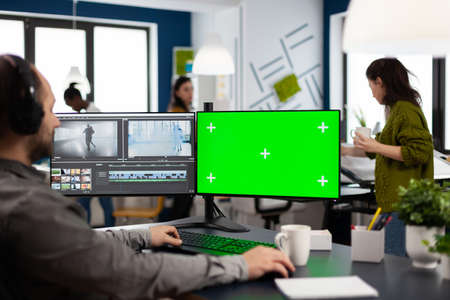 Man editor processing film montage on pc with green screenの写真素材
