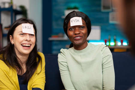 Mixed race people having fun, laughing together while sitting on sofa late at night.