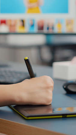 Close up of color designer freelancer photographer editing customer photo using computer with two displays and stylus pen. Graphic editor retouching assets drawing on graphic tablet in creative agencyの写真素材