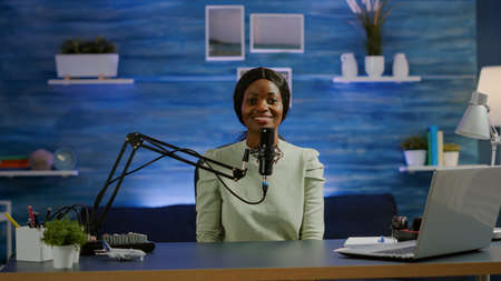 Portrait of african vlogger working in cozy studio, smiling at camera ready to start new podcast...