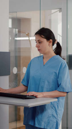 Front view of assistant typing medical expertise on computer while in background afro american...