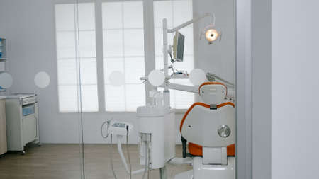 Empty dental orthodontic chair in dentistry stomatology hospital room with nobody in it. Modern orthodontist clinic equipped with professional furniture and tooth instruments ready for oral surgeryの写真素材