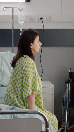 Medical nurse black woman checking hospitalized sick patient with respiratory disorder recovering after illness surgery. African assistant working in hospital ward discussing treatment with patientの写真素材