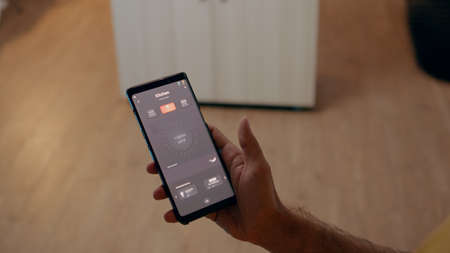 Close up of man using voice activated application to turn on bulbs in smart home with automation...
