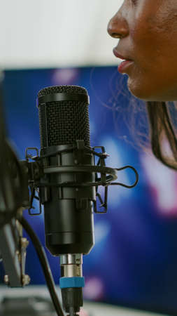 African professional space shooter streamer discussing strategy with teammates talking into microphone. Streaming viral video games for fun using RGB computer and keyboard for online championship.の写真素材
