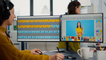 Professional graphic editor retouching photos of a client on PC with two displays color grading...