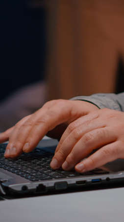Close-up of businessman hands on keyboard sitting at desk table in startup company office browsing economic ideas on internet. Entrepreneur typing financial statistics answering business emailの写真素材