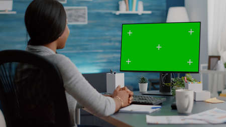 African american woman working remote from home listening school professor explaining online course. Student looking at mock up green screen chroma key display during virtual videocall meeting conferenceの写真素材