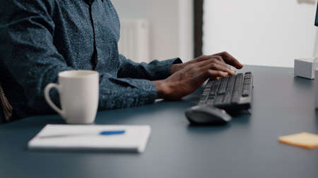 Black african american manager working from home, tuping on computer keyboard. Panning close up shot from hands to the face. Bright nice home officeの写真素材