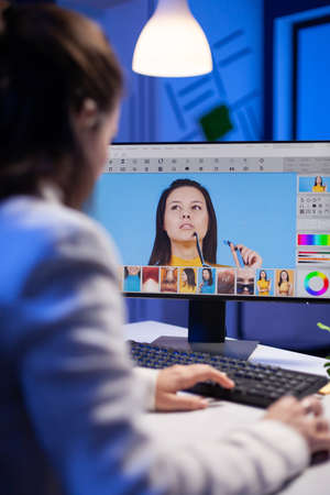 Creative creator doing portrait retouch using color grade late at night in professional editing office. Graphic editor retouching photos of a client on performance pc before deadlineの写真素材