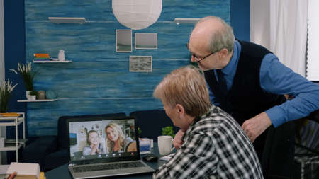 Happy old senior couple grandparents waving at laptop computer during video conference calling,...