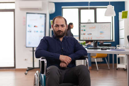 Sad businessman frustrated of his disabilities looking at camera sitting immobilized paralysed in...