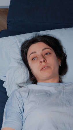 Sad desperate depressed young woman sitting alone crying lying on sofa in dirty room suffering from anxiety, loneliness mental health problem regret dramatic mistake suicide thoughts chronic diseaseの写真素材