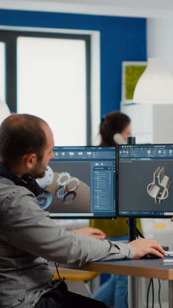 Diverse team of engineers working on computer at mechanical piece design cad sharing ideas about...