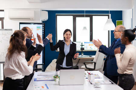 Happy diverse coworkers applauding after successful presentation. Multiethnical partners coworkers celebrate successful teamwork result at company briefingの写真素材