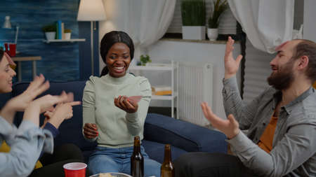 Multiracial friends playing Guess who game with sticky papers attaching on forehead. Mixed race...