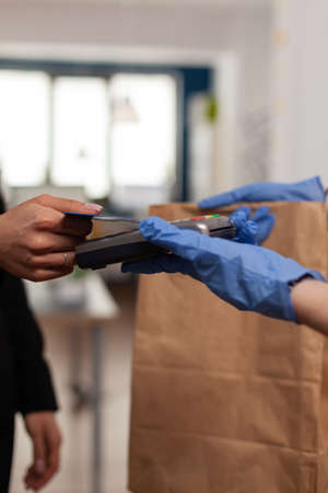 Closeup of businesswoman paying takeaway food order with credit card using POS contactless service...