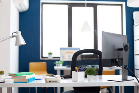 Modern office interior with nobody in it for business people to work. Inside view of stylish space of startup workplace corporate. Monitor with financial statistics and charts.の写真素材