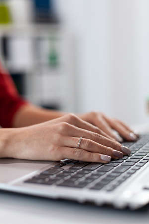 Close up of businesswoman manager hands fingers typing documents on laptop keypad. Detail shot of...