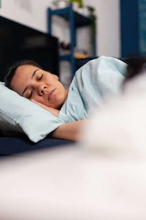 Woman feeling sick sleeping at home on the couch, recovering after cold and flu symptoms. Having...