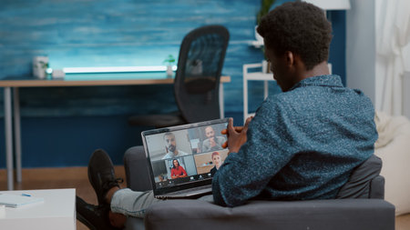 African american man using laptop for online internet conference chat with his coworkers, remote working from home, teleconference web communication with webcam. Black guy distance technology talkingの写真素材