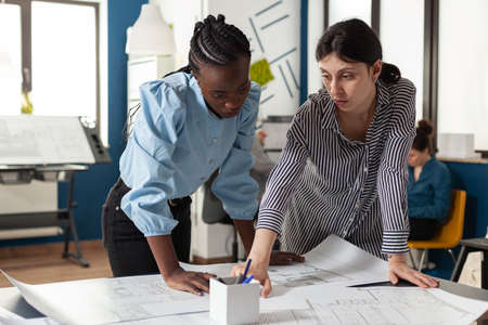 Architectural team of multi ethnic women plan sketch blueprint layout for design project building...