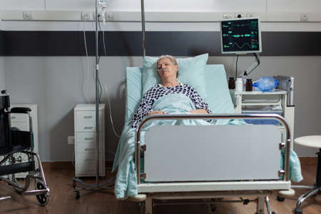 Senior woman patient laying in hospital bed with oxymeter attached on body, measuring oxygen...
