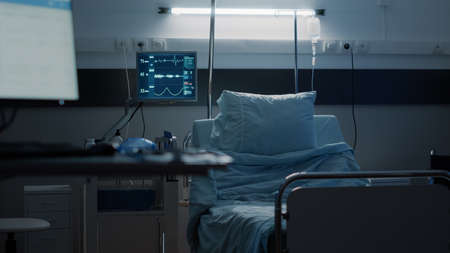 Empty hospital ward designed with medical equipment used as treatment for disease, illness, health problems. Intensive care room with medical tools, monitor, IV drip bag and oxygen tubeの写真素材