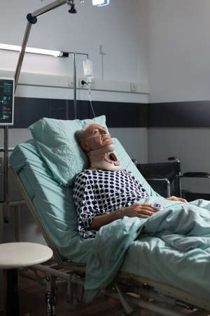 Senior man suffering after serious accident laying in hospital bed, wearing neck brace. Patient with...