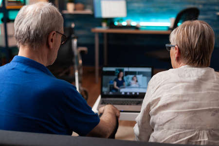 Retired couple talking on video call online conference technology at home to sick woman and child in...