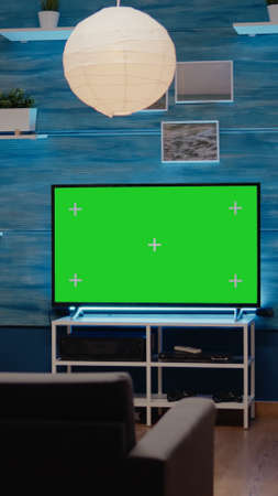 Nobody in living room with green screen display in modern decorated flat. Television with chroma key with isolated background using copy space and mockup templateの写真素材