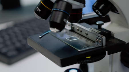 Close up of microscopic sample tray for optical analysis in laboratory. Microscope with magnifying lens used for dna and bacteria investigation in pharmaceutical research industryの写真素材