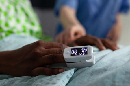 Close up of oximeter on african american girl hand laying in hospital ward bed. Device showing low oxygen saturation and pressure measurement used on young patient with disease. Medical equipmentの写真素材