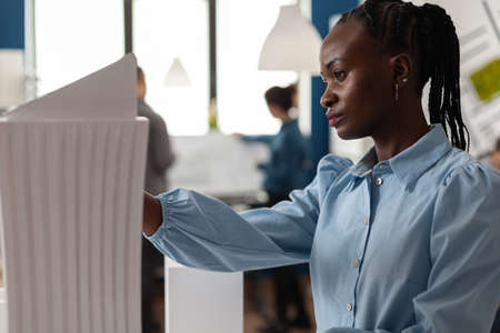 African american architect constructor at office working on building model plan design maquette. Afro woman looking at modern layout of construction for development projectの写真素材