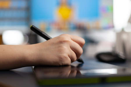 Close up of designer retoucher photographer hand editing customer photo using computer with two displays and stylus pen. Graphic editor retouching pictures drawing on graphic tablet in studioの写真素材