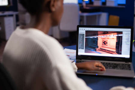 African american game developer testing new game working late at night in creativity agency company. Tired creator designer developing online video games on pc using modern production technologyの写真素材