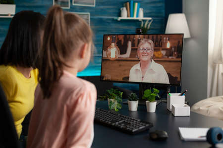 Mother and daughter using video call conference technology for modern communication. Adult and child...