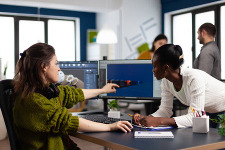 Diverse women game developers creating game interface sitting in startup creative production company...